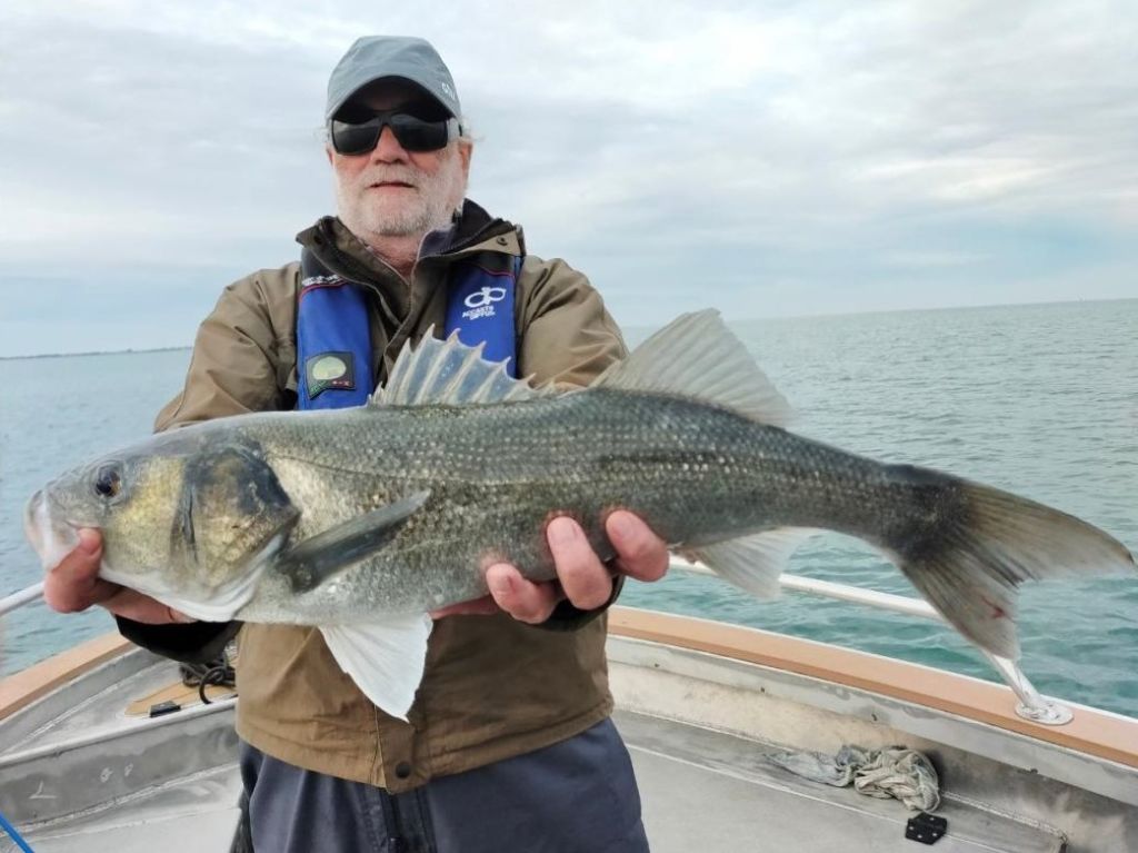Pêcheur avec un bar pêché en mer